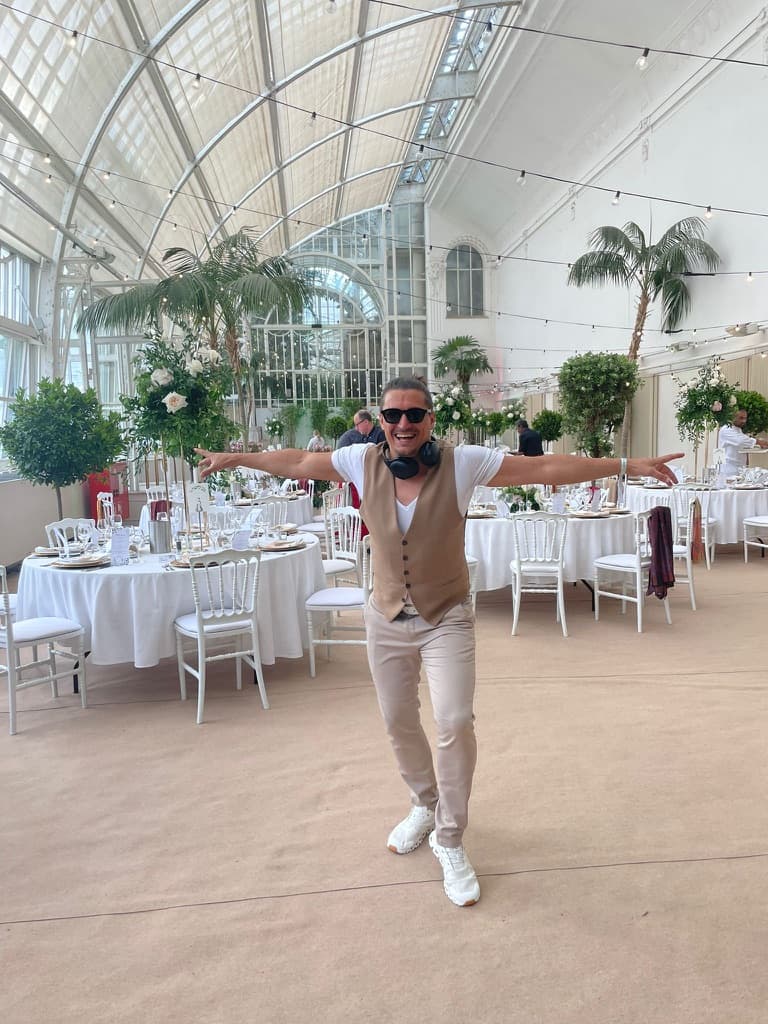 Steve Manera beim Aufbau in einer Glas-Orangerie mit weiß gedeckten Tischen und Palmen