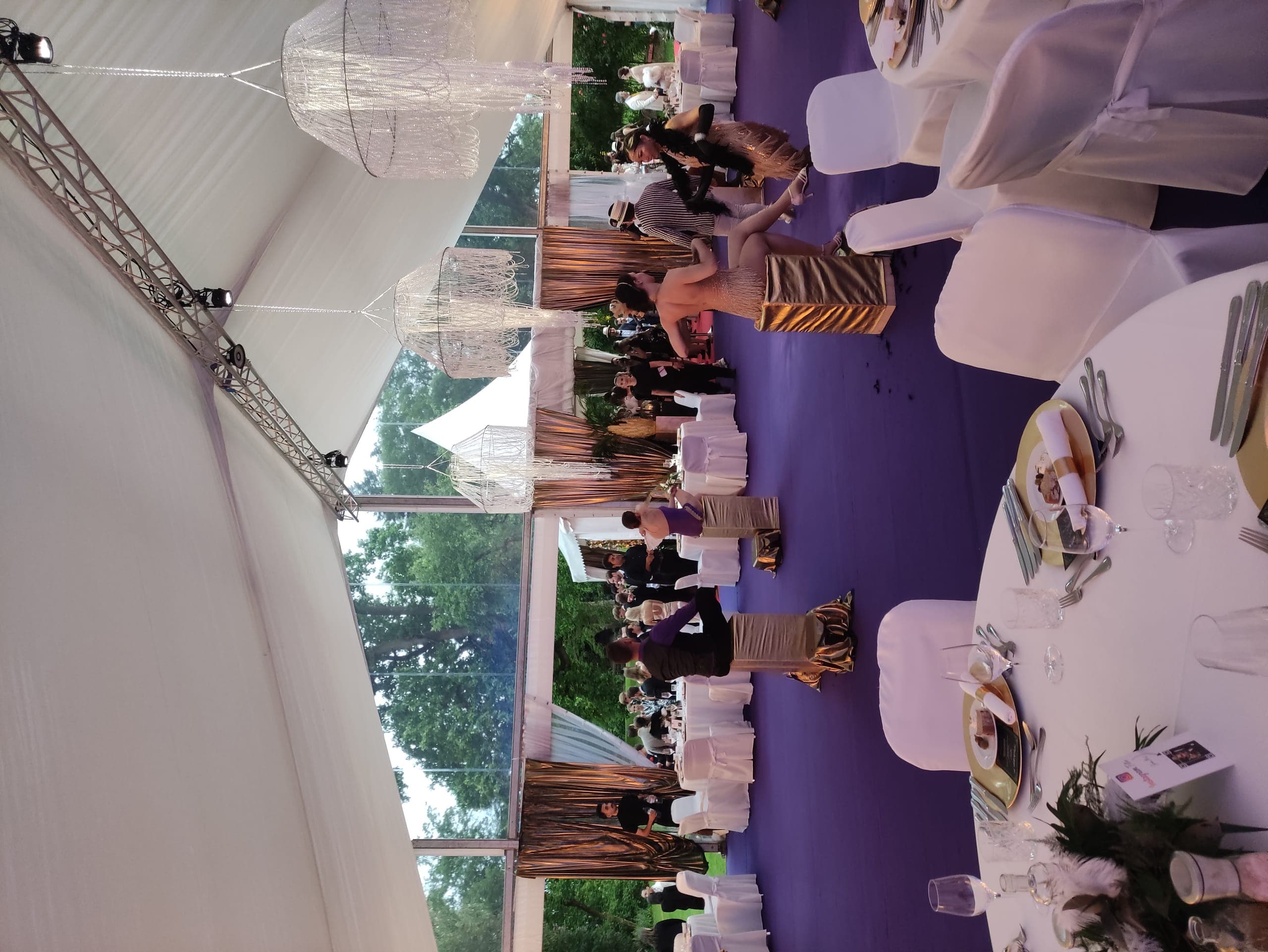 Festlich dekorierte Zelt-Reception am Abend mit Lustern und Gästen