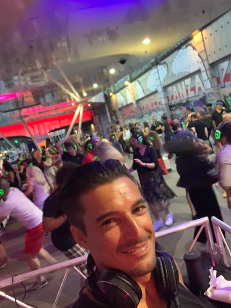 Steve Manera am Pult einer Silent-Disco-Straßenparty — volles Open-Air-Publikum bei Nacht